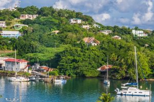 Scenic harbor in St. Lucia with sailboats and fishing boats anchored in calm blue water, colorful buildings, and lush green tropical hillside