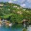 Scenic harbor in St. Lucia with sailboats and fishing boats anchored in calm blue water, colorful buildings, and lush green tropical hillside
