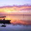 Stunning sunset in Spanish Wells, Bahamas with a small boat silhouetted against pink and orange sky reflecting on calm water