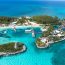 Stunning aerial view of Blue Lagoon Island in the Bahamas with turquoise Caribbean lagoons, white sandy beaches, palm tree groves, water sports equipment, and private island resort facilities