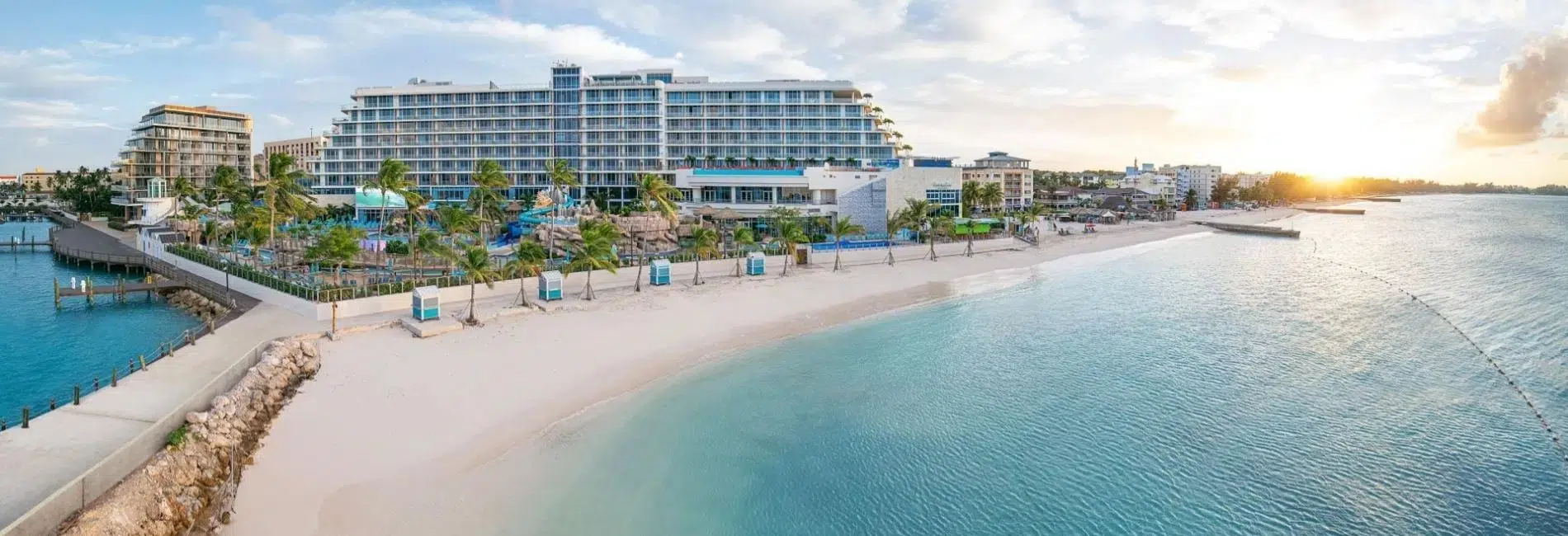 Bahamas Beachfront Hotel Resort with Turquoise Water and White Sand Modern beachfront hotel resort in the Bahamas with turquoise water, white sand beach, palm trees, beach cabanas, boardwalk, and waterfront views at sunset
