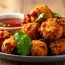 Crispy golden conch fritters, a traditional Bahamian appetizer, garnished with cilantro and served with tangy dipping sauce