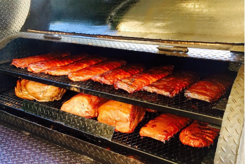 BBQ ribs and pork shoulder smoking at Rincón Smoke Shack in Puerto Rico with glazed rack of ribs and tender smoked pork on professional smoker grates