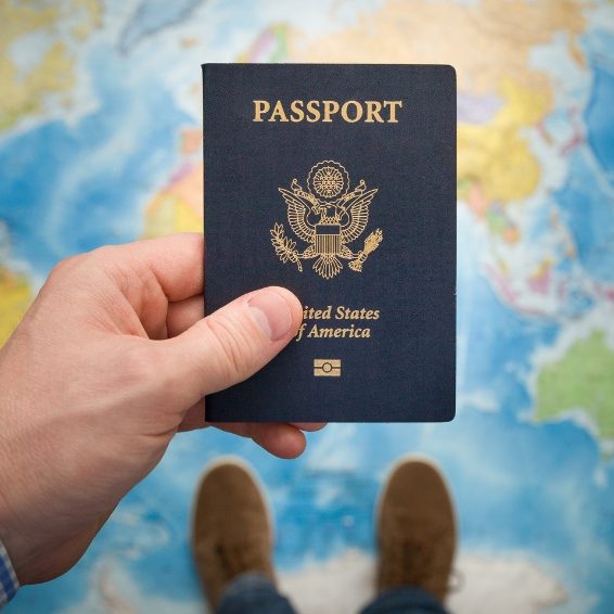 Puerto Rico Travel Requirements US Passport with World Map Hand holding United States passport over colorful world map representing travel requirements and documentation for Puerto Rico travel